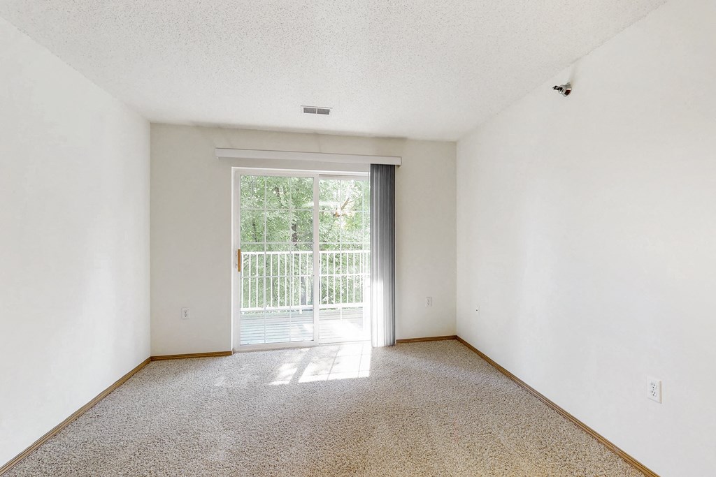 an empty living room with a door to a balcony