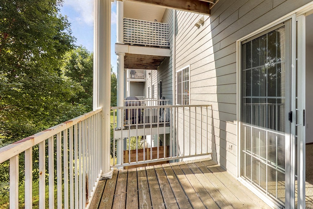 a balcony with a deck and a door to a house