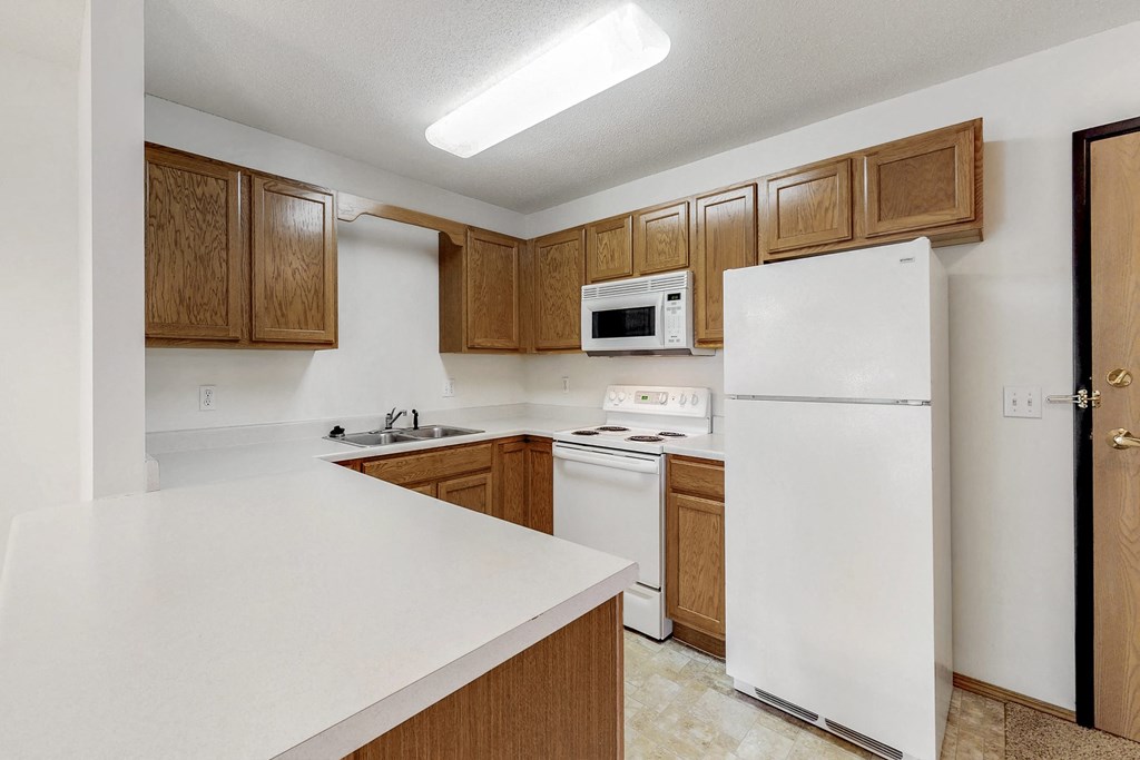 an empty kitchen with white appliances and wooden cabinets
