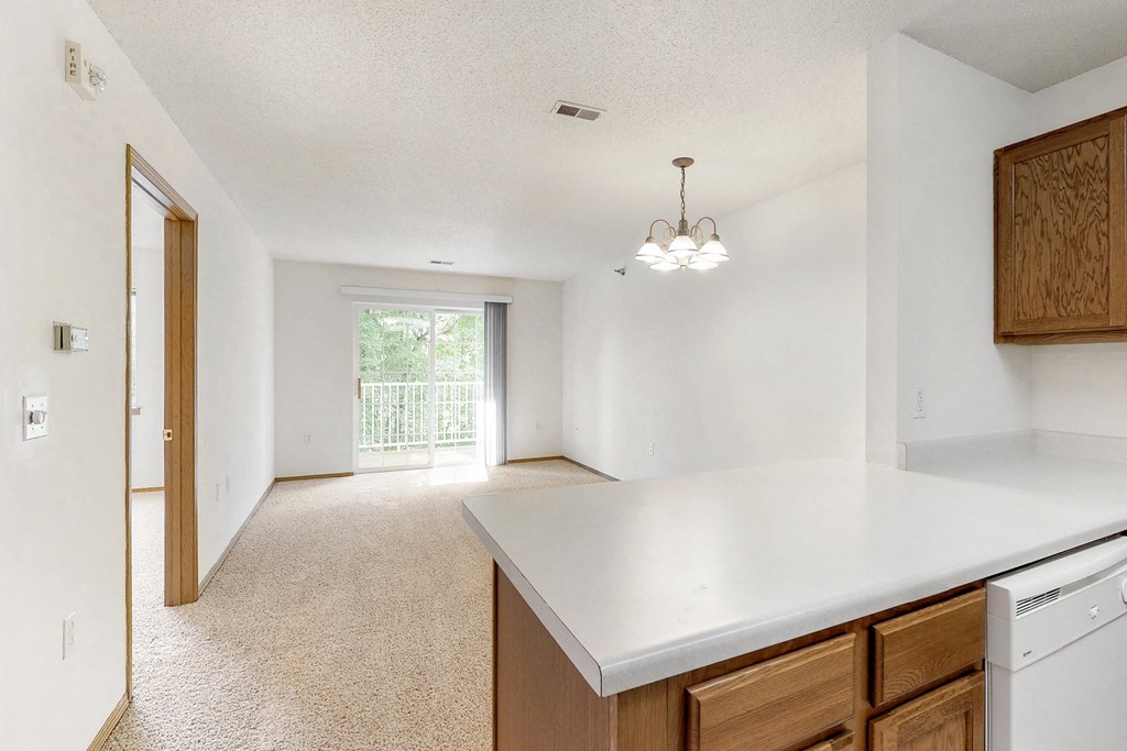 an empty kitchen and living room with a door to a balcony