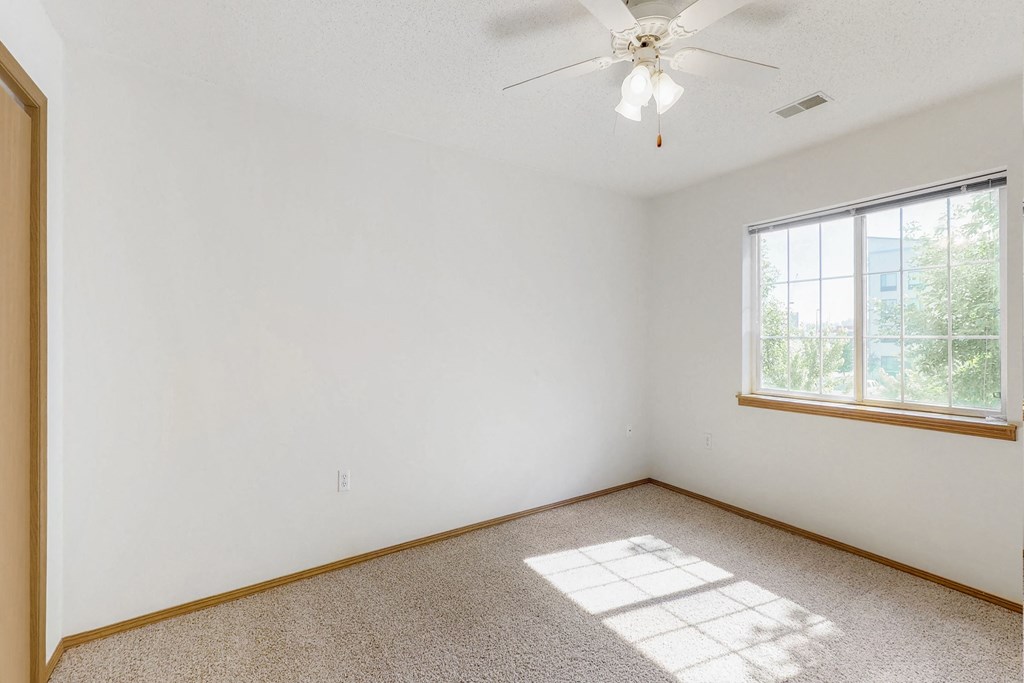 an empty room with a window and a ceiling fan