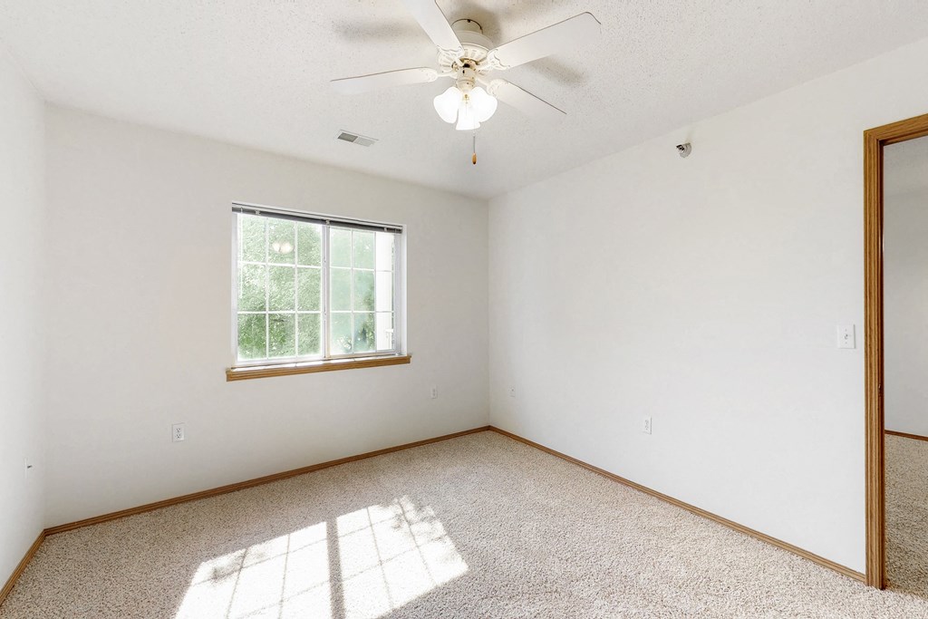 an empty room with a ceiling fan and a window