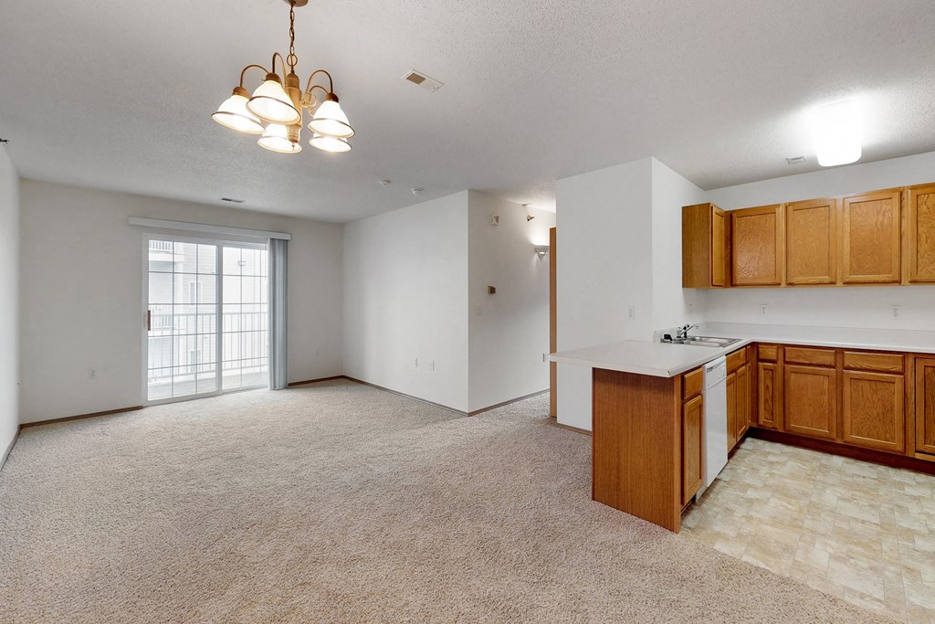 an empty living room and kitchen with wood cabinets