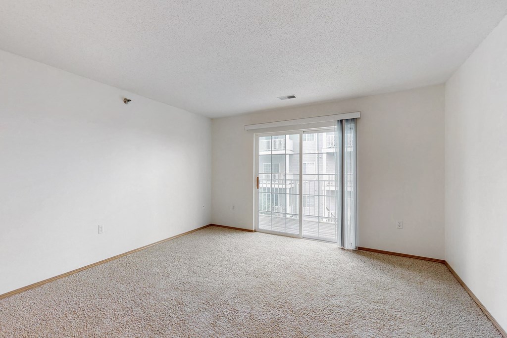 an empty living room with a door to a balcony
