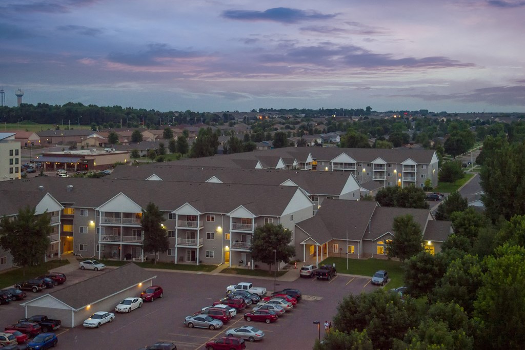 an aerial view of an apartment complex with cars parked at dusk