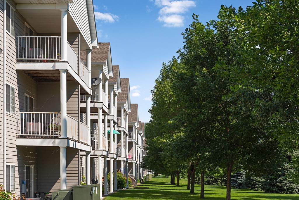 a row of apartments with balconies and trees in the grass