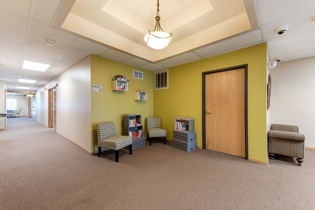 a hallway with chairs and a door      and a yellow wall
