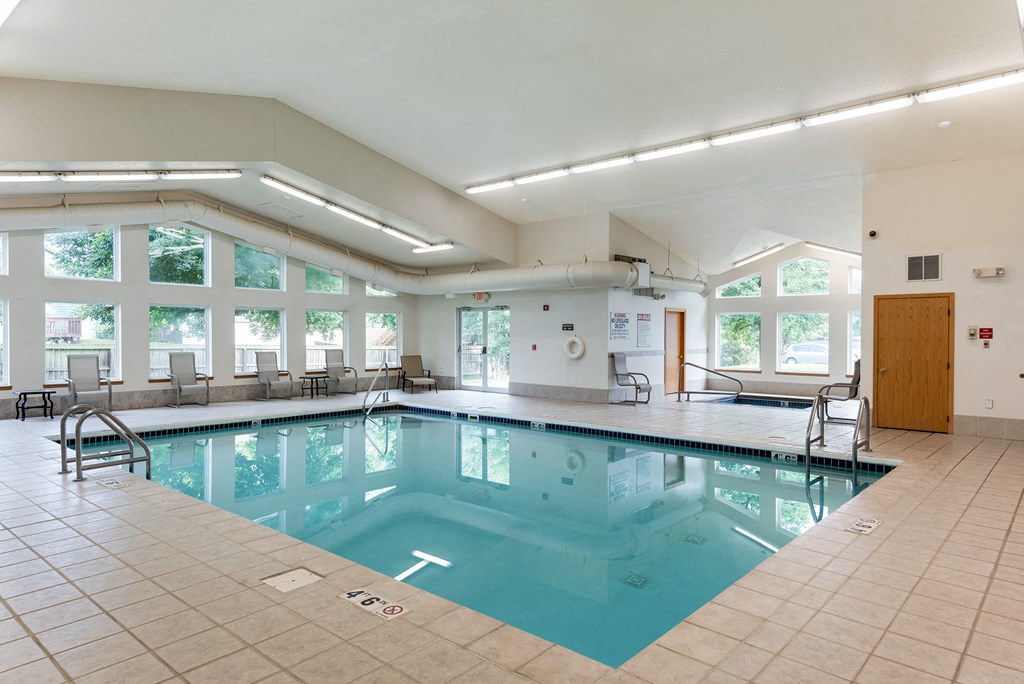 a swimming pool in a large room with chairs and windows