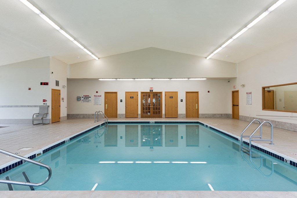 a swimming pool in a large room with wood floors and a blue pool