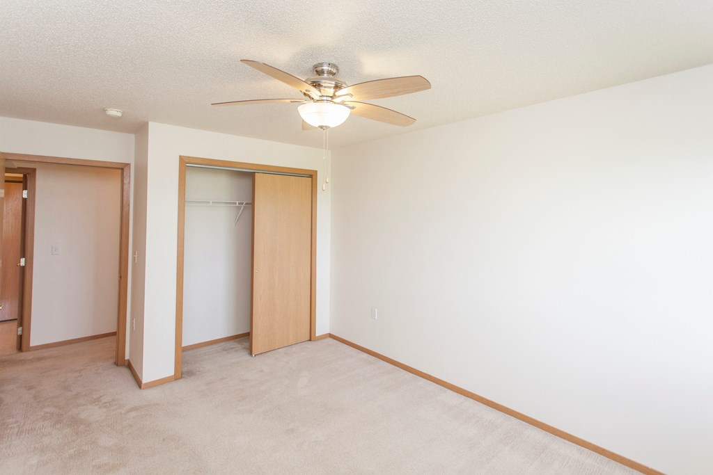 a empty room with a ceiling fan and a closet