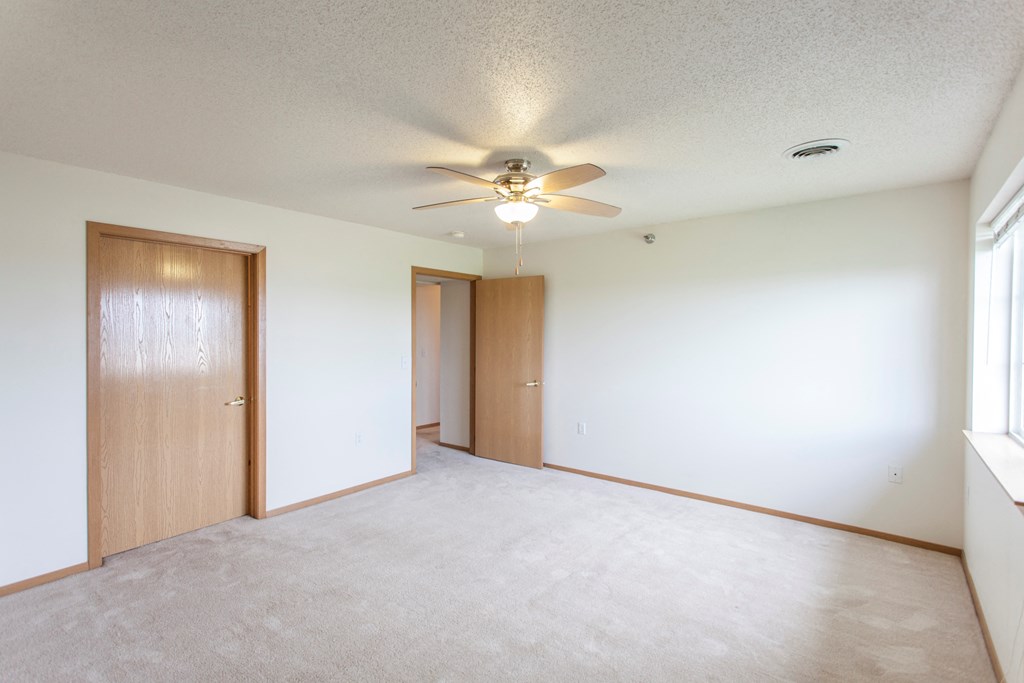 the living room of an empty apartment with a ceiling fan