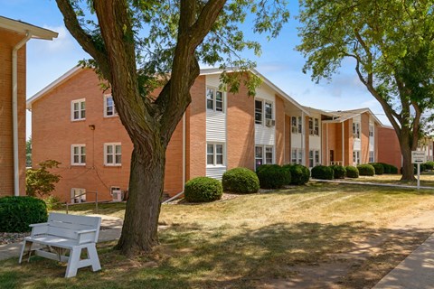 a white bench sits in front of a brick building