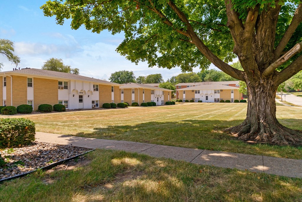 a building with a tree in front of it and a sidewalk