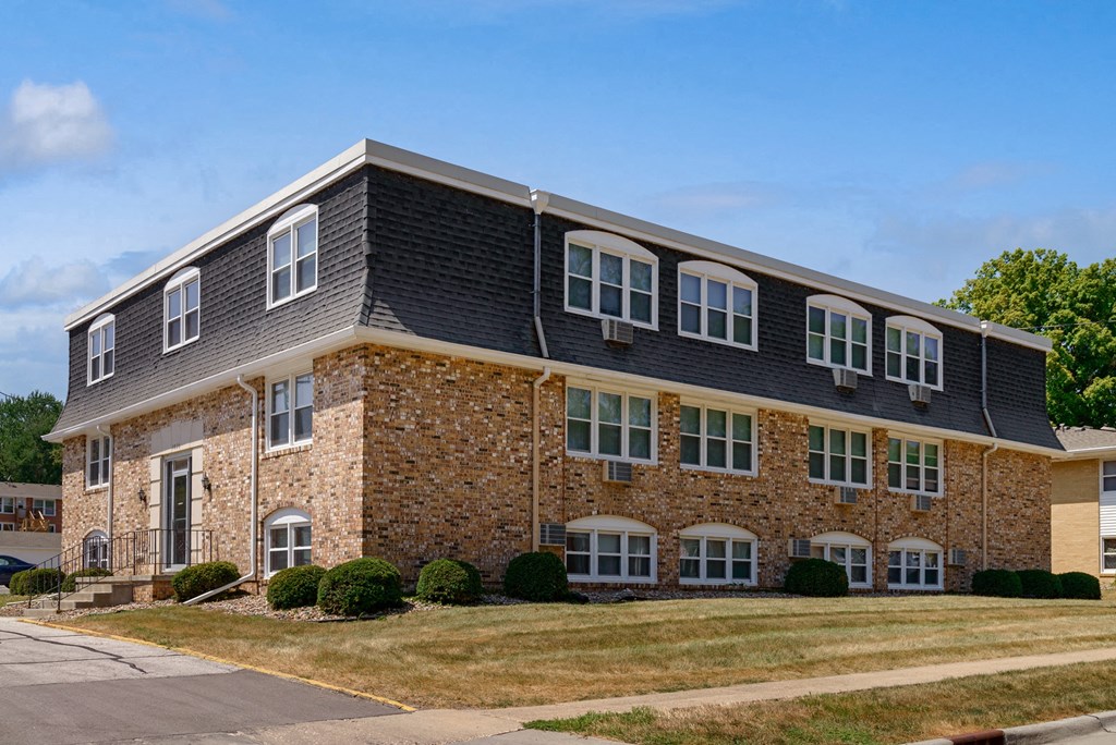 a brick building with a black roof and white windows
