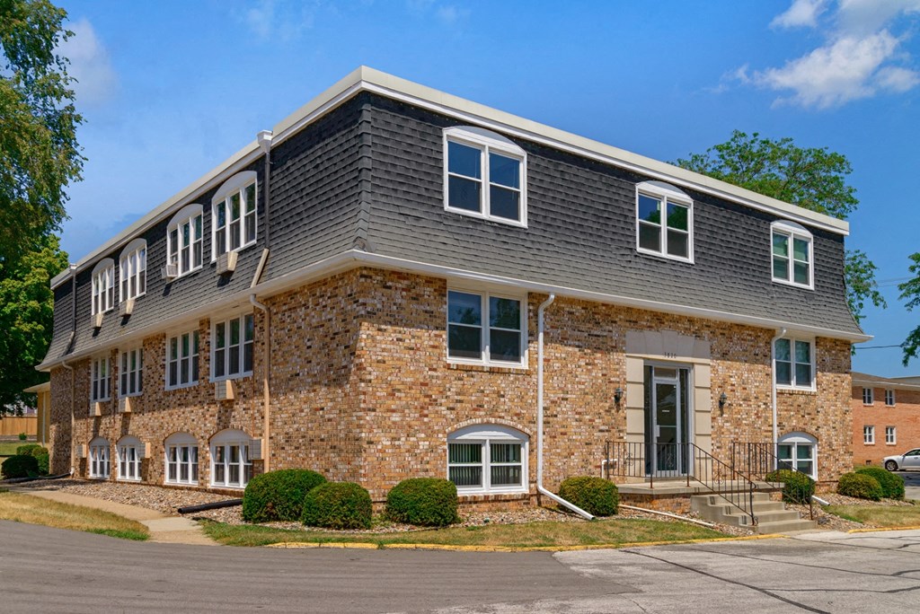 a brick building with a gray roof and white windows