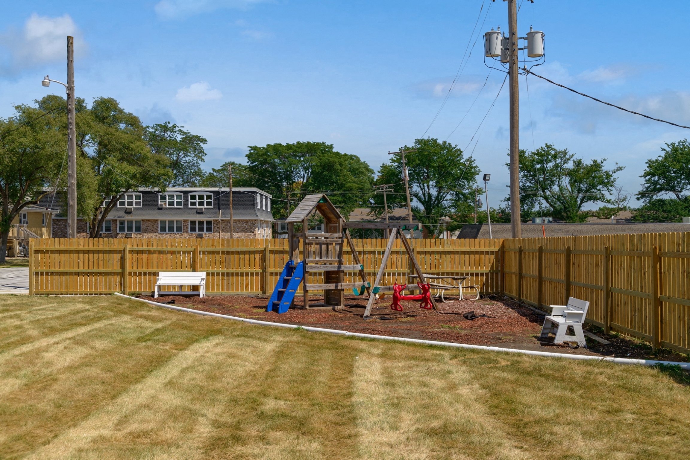 a playground with a swing set in a fenced in yard