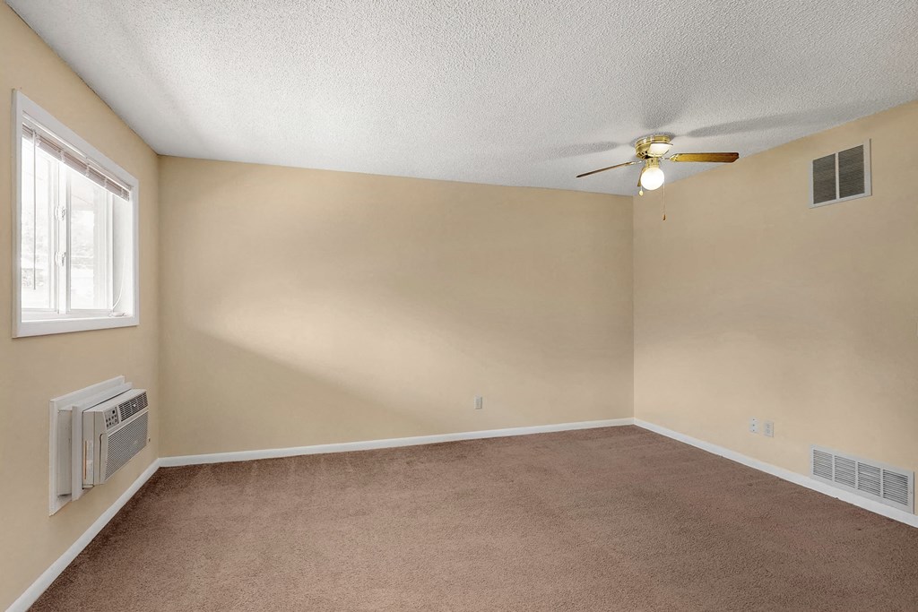 an empty living room with a ceiling fan and a window
