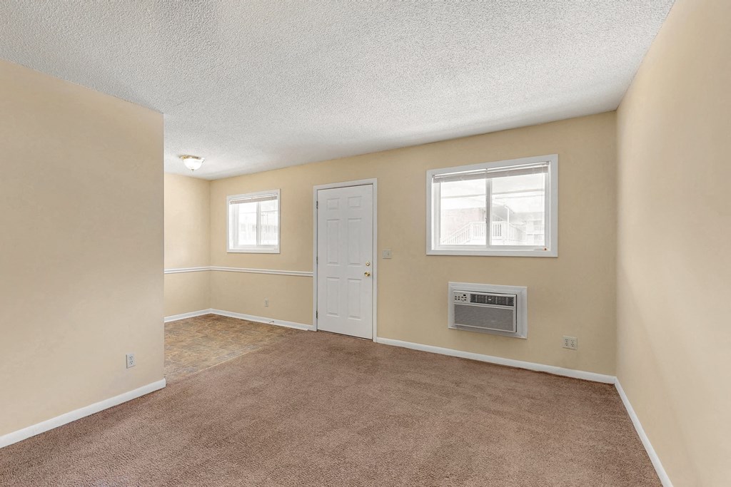 an empty living room with a door and window