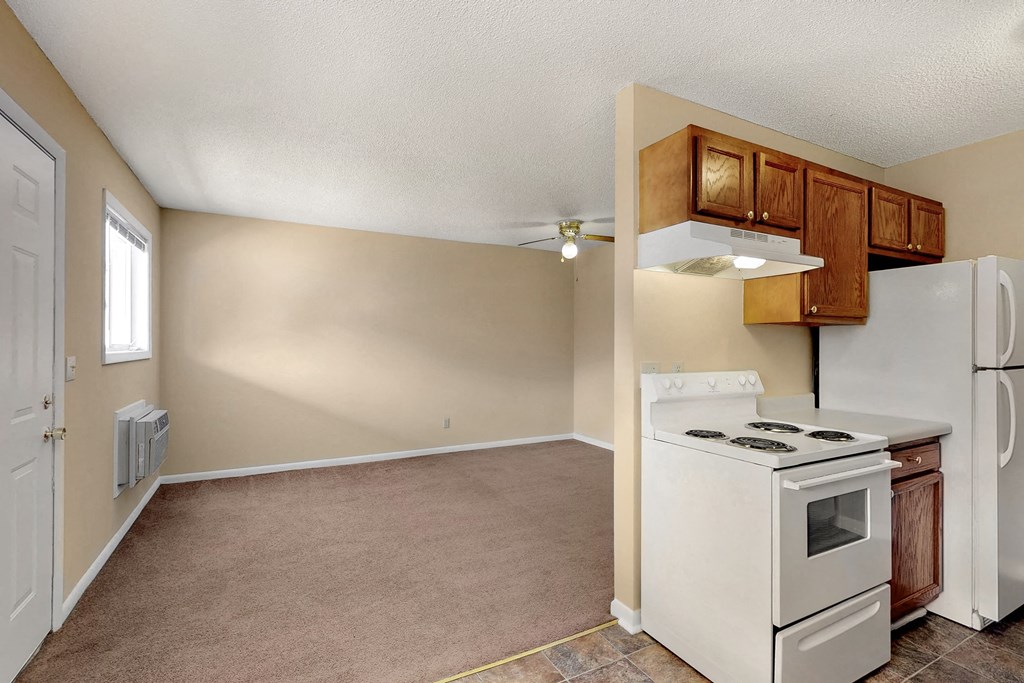 an empty kitchen with a white stove and refrigerator