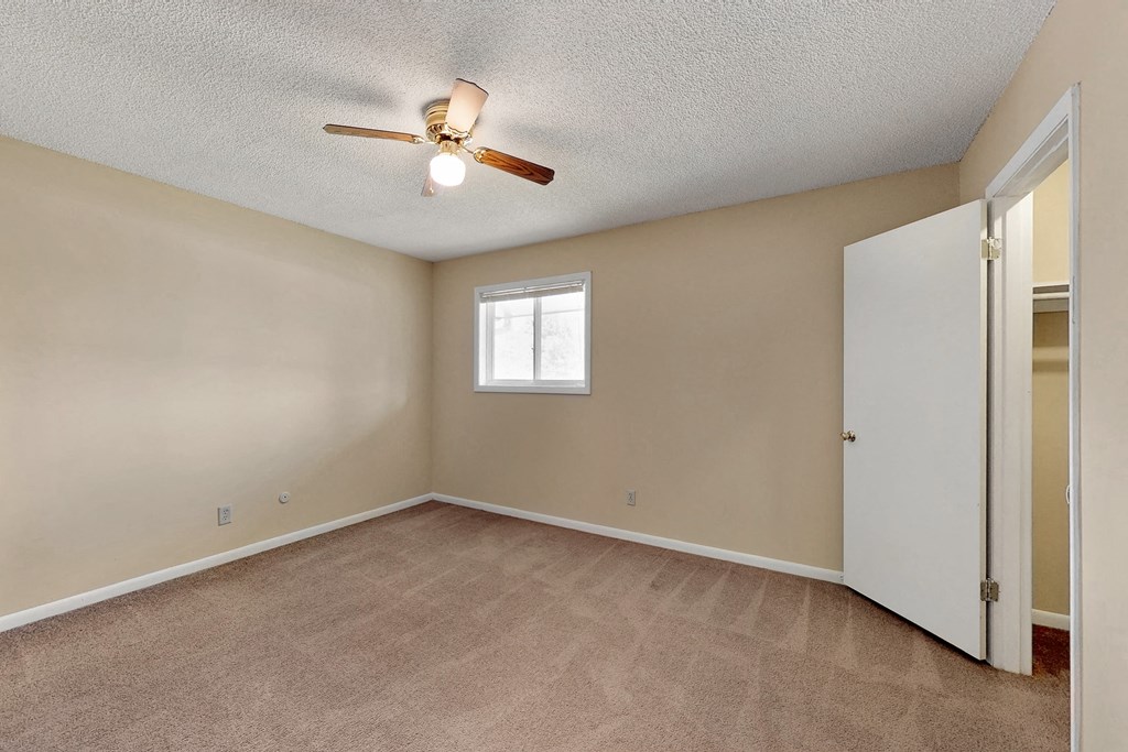 an empty living room with a ceiling fan and a closet