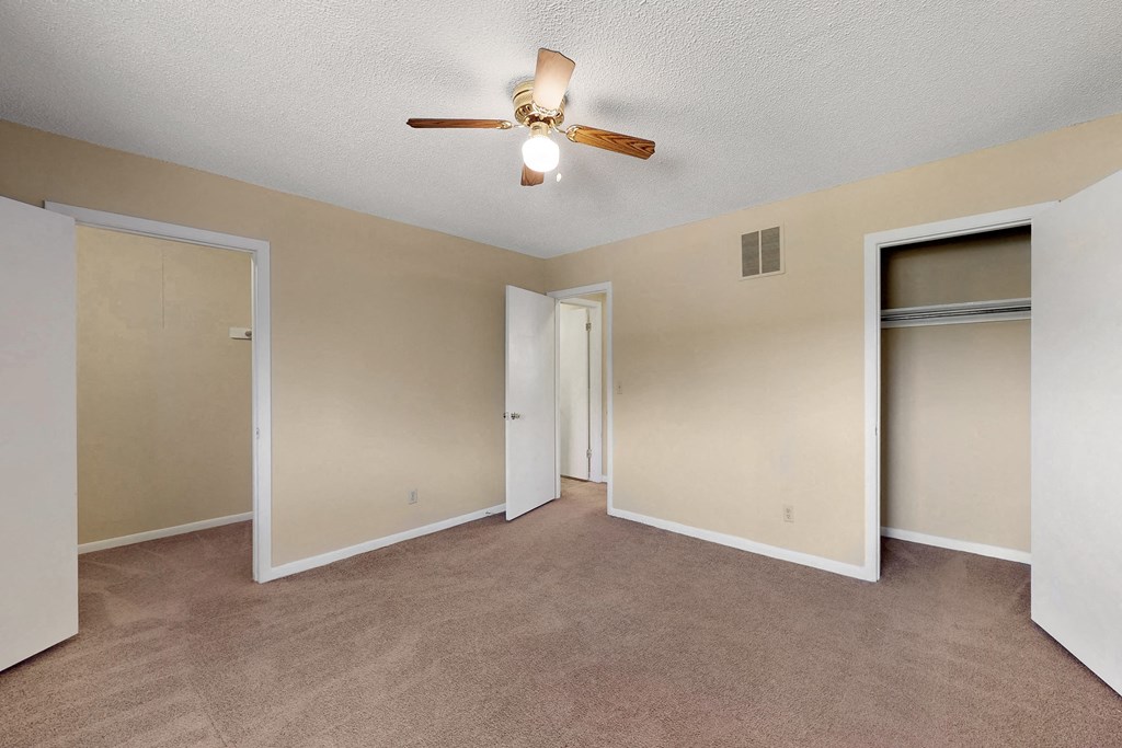 an empty living room with a ceiling fan and a closet