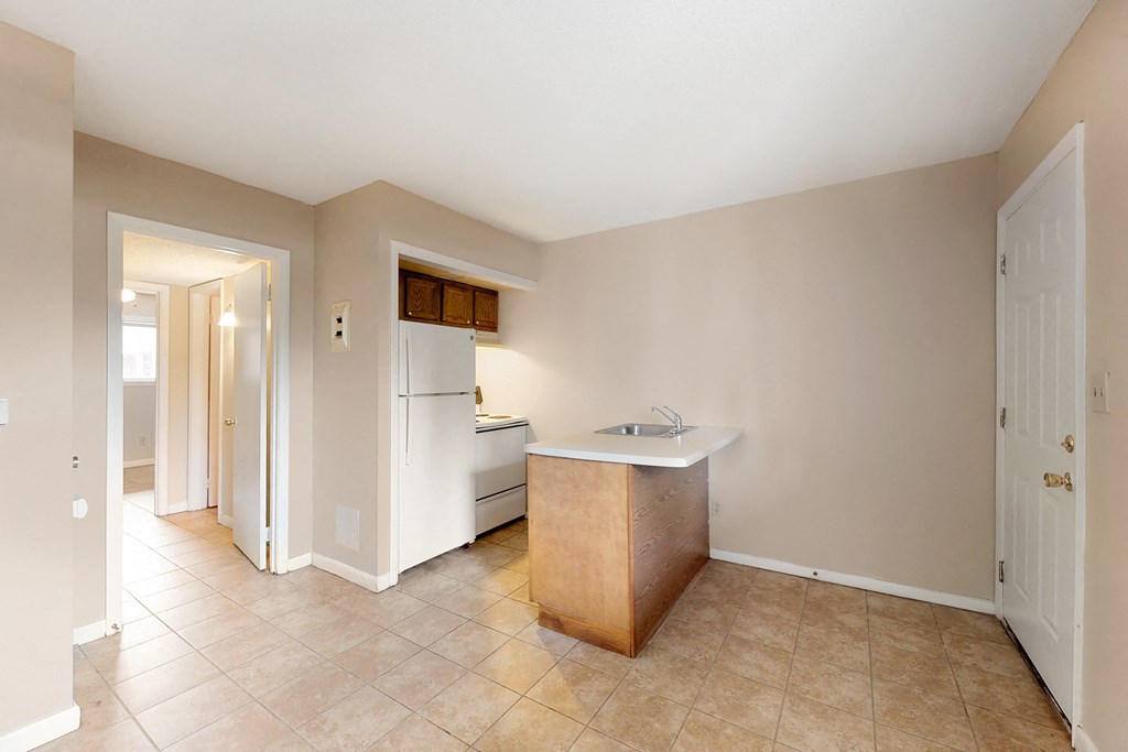 an empty kitchen with a sink and a refrigerator