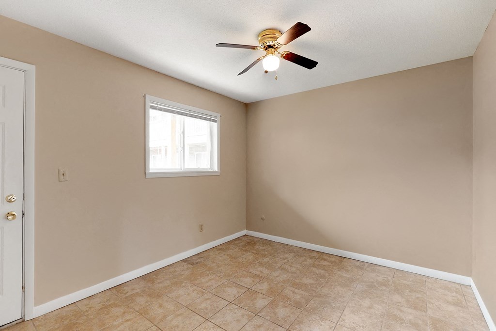 an empty living room with a ceiling fan and a window