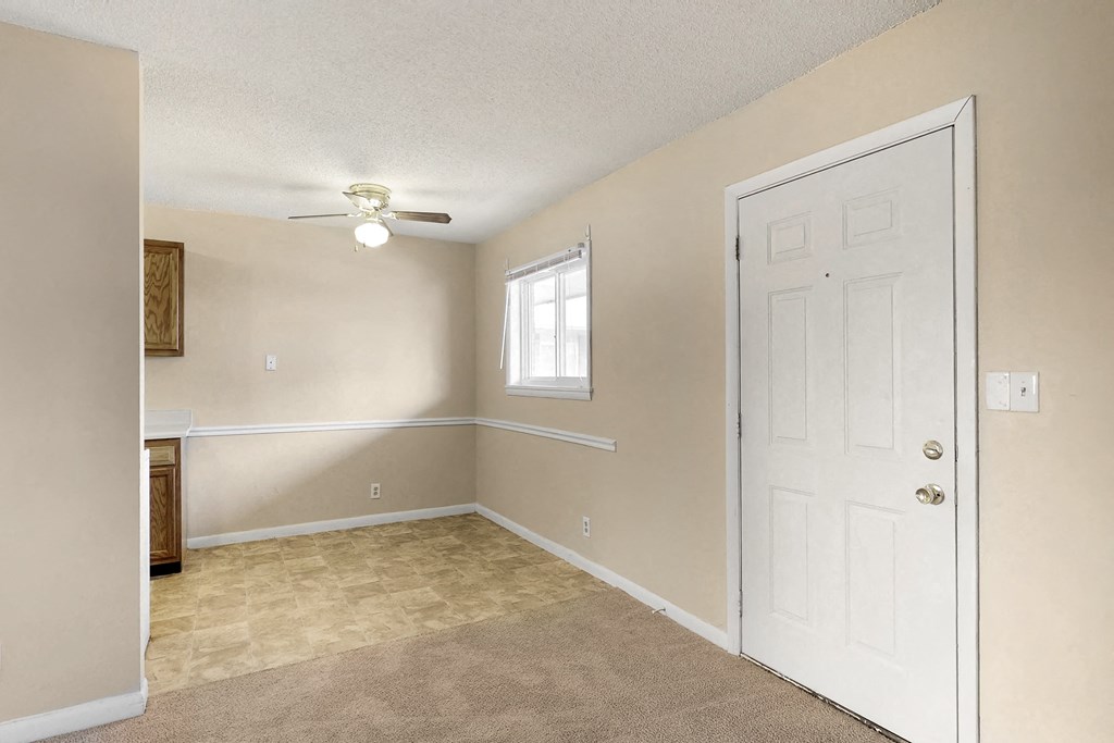 an empty living room with a white door and a window