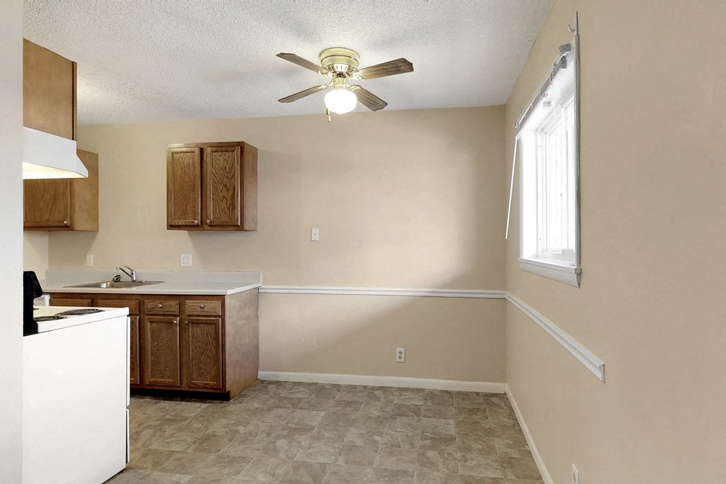 an empty kitchen with a ceiling fan and a window