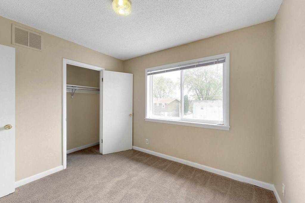 an empty bedroom with a large window and a closet