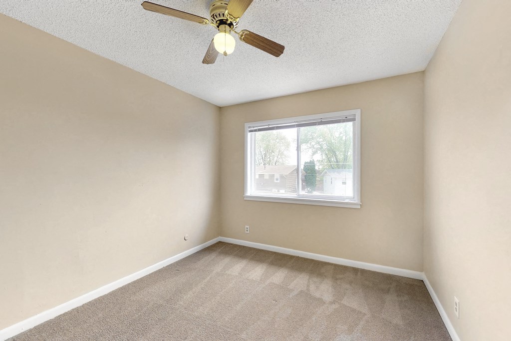 an empty living room with a ceiling fan and a window