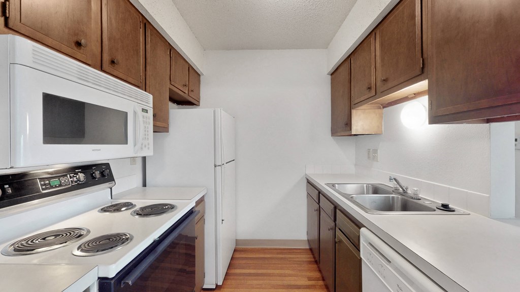 an empty kitchen with white appliances and wooden cabinets