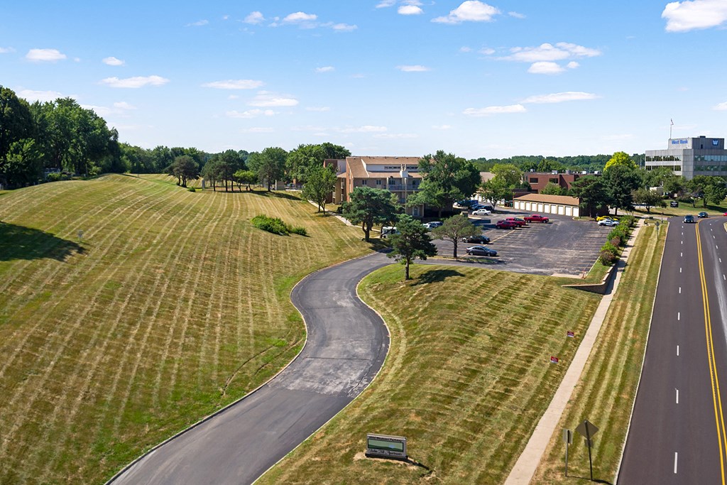 an aerial view of a road next to a field and a building