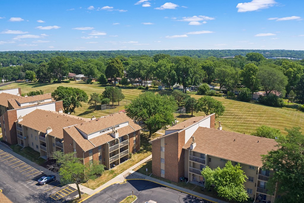 an aerial view of an apartment complex with a field and trees