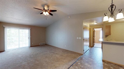 A spacious room with a ceiling fan and sliding glass doors.