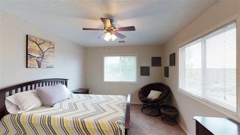 A bedroom with a bed, a chair, and a ceiling fan.