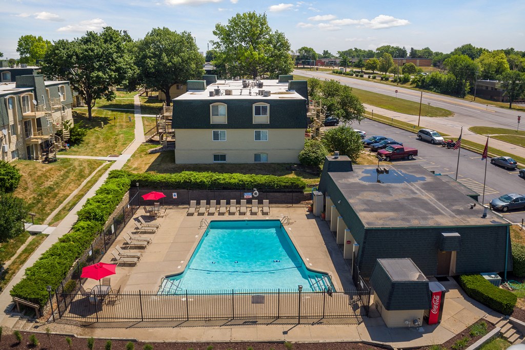 an aerial view of a swimming pool in front of a hotel and a building with