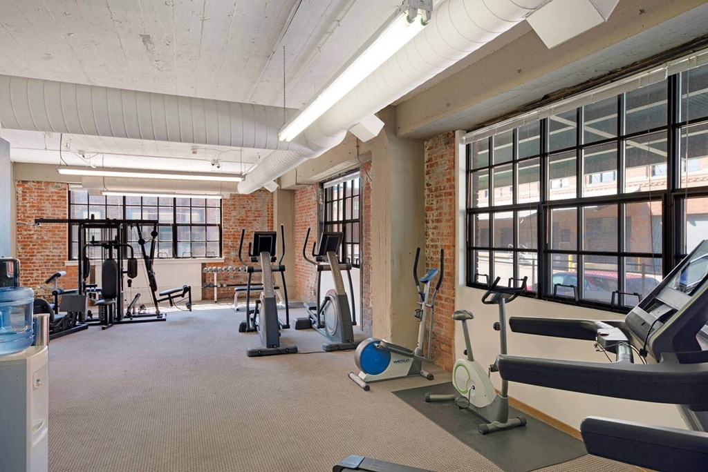 a gym with exercise equipment and windows in a loft