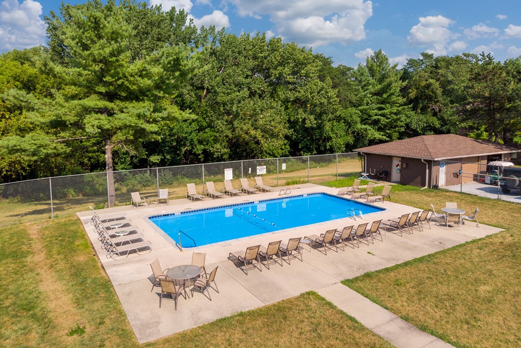 an aerial view of a pool with chairs and tables around it
