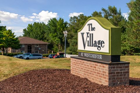 the village sign in front of thevillage apartments