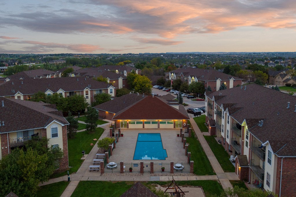 an aerial view of a swimming pool in the middle of a neighborhood with houses