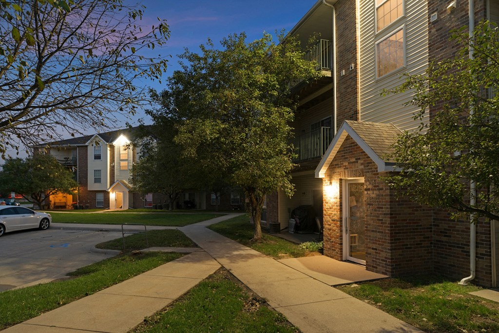 a sidewalk in front of an apartment building at night