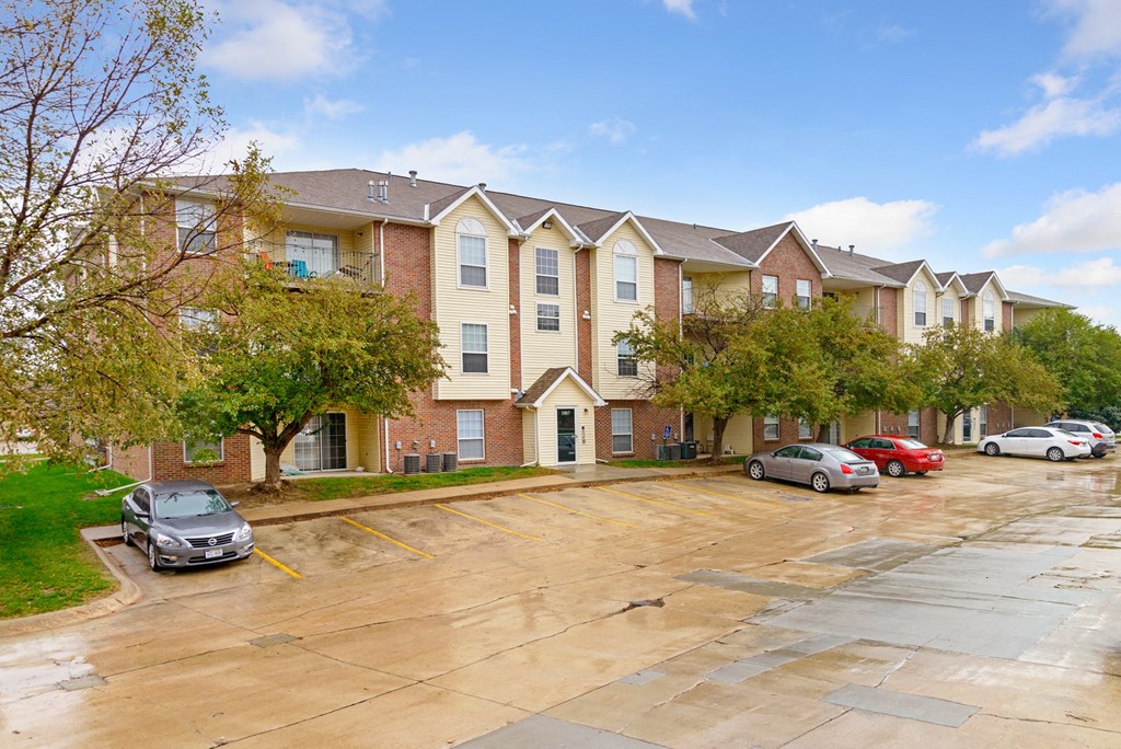 a large apartment building with cars parked in a parking lot