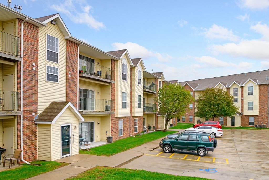 a row of apartment buildings with cars parked in a parking lot