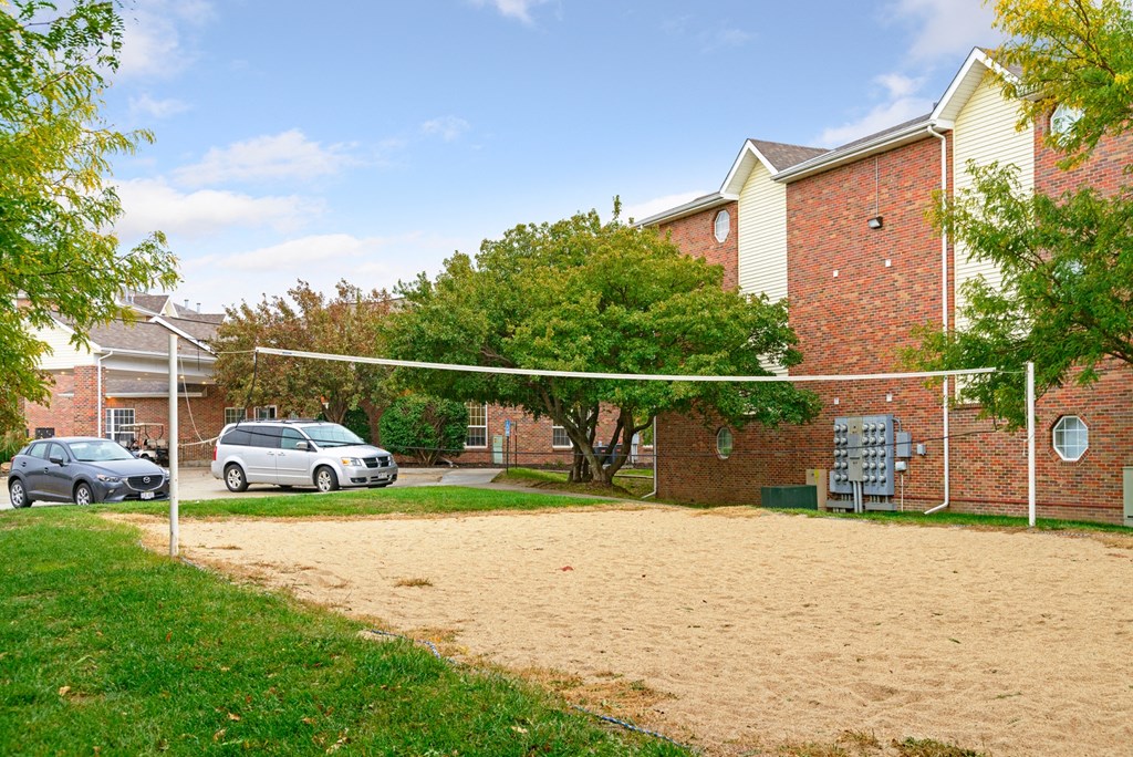 a sandy volleyball court in front of a brick building