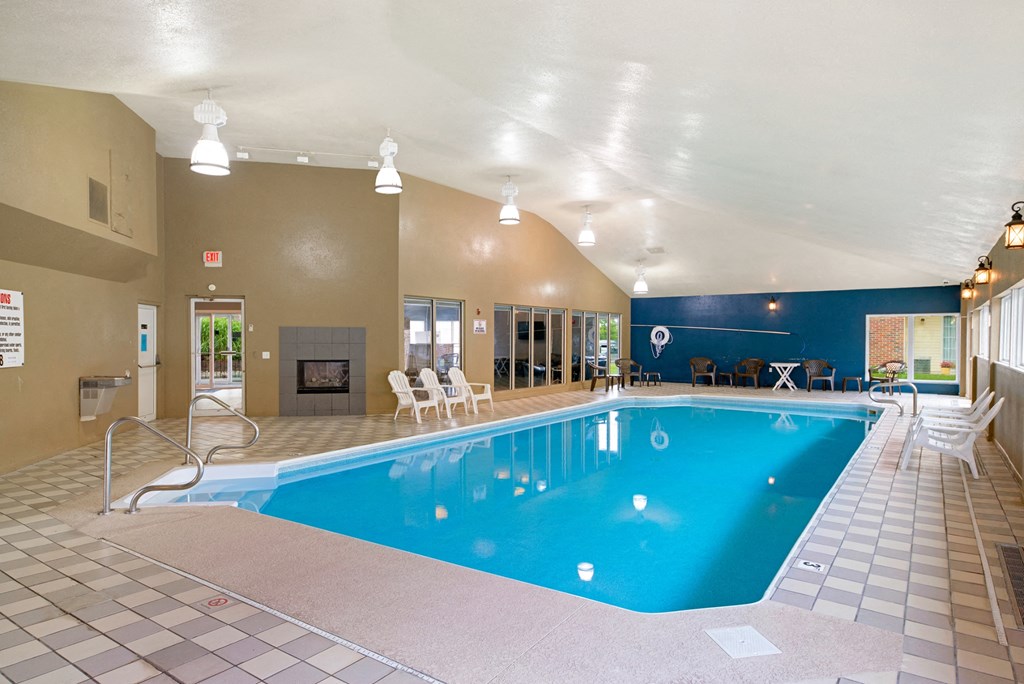 a swimming pool with chairs and a fireplace in a hotel room