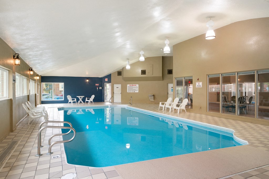 a swimming pool in a building with chairs and a blue pool