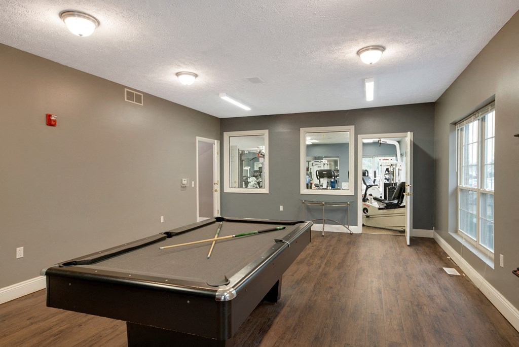 an empty game room with a pool table and windows