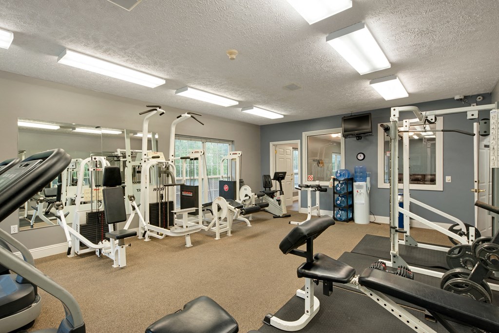 a gym with cardio equipment and weights on the floor