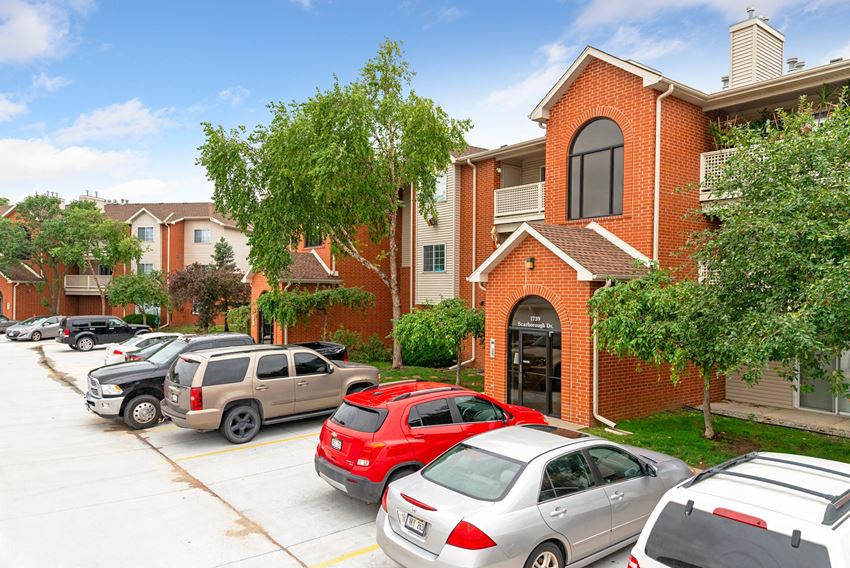 a parking lot in front of a brick building with cars parked in front